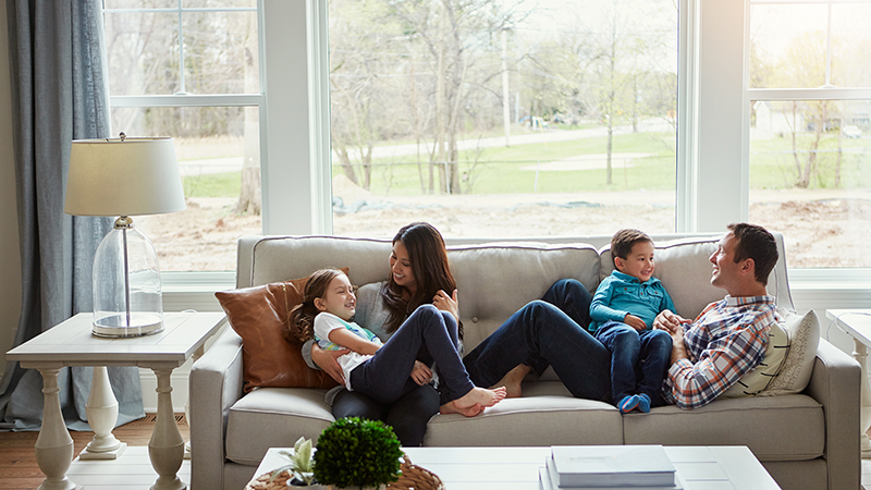 Family sitting on couch in a well insulated home. Sun shining through windows.